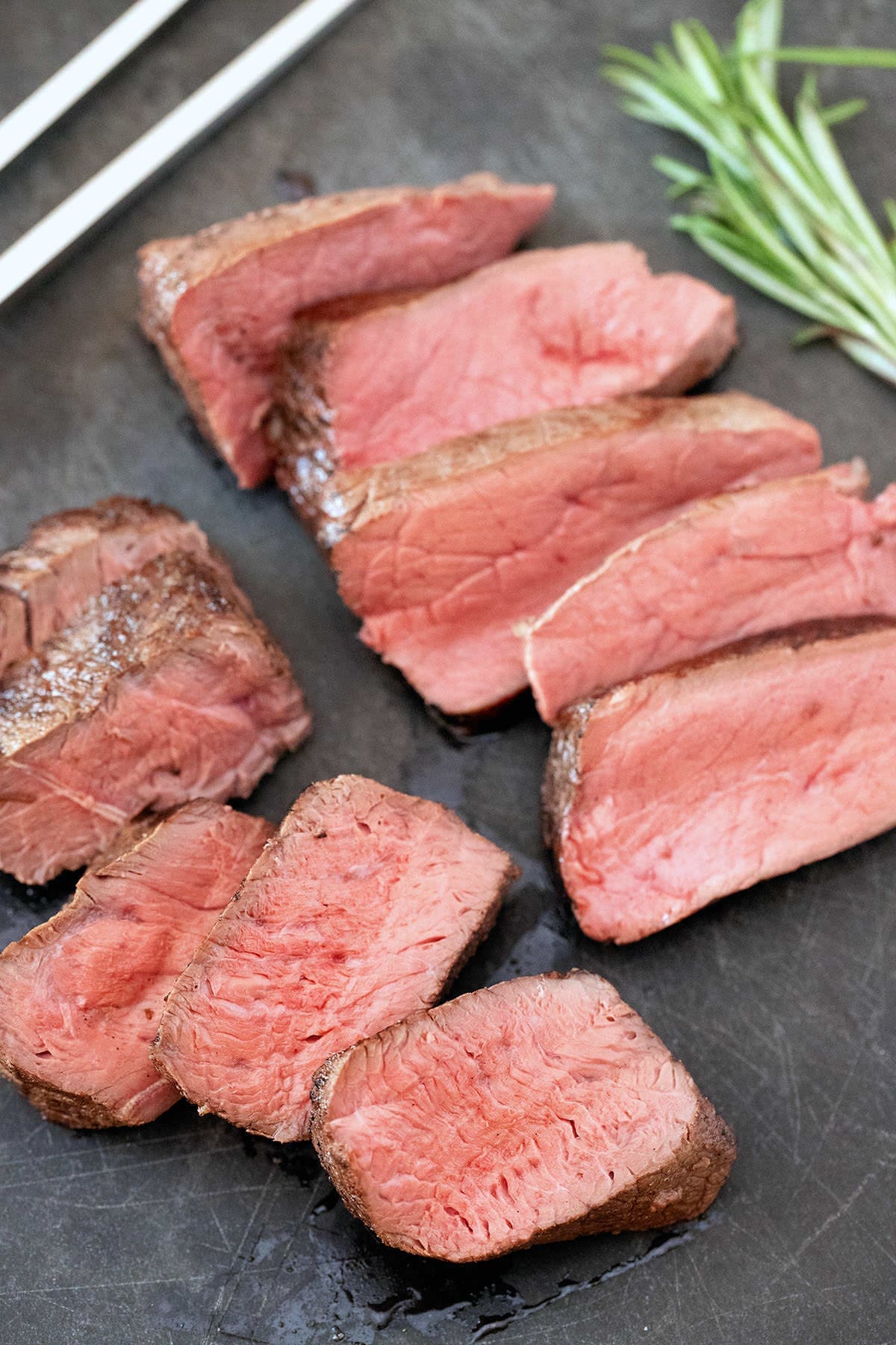 Sous Vide Sirloin Filet (+ Secret Ingredient) 6 Sliced petite filets on a black cutting board.