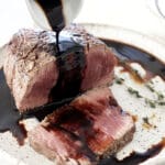Balsamic Glaze being poured over a cut steak.