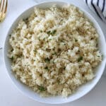 White bowl of cheesy rice with a gold fork.