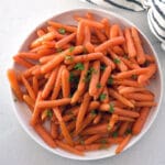 White plate of roasted baby carrots.