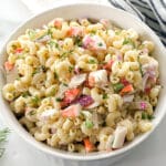 White bowl full of crab pasta salad with fresh dill.