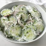 White bowl full of creamy cucumber salad.