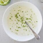 White bowl filled with lime crema and a spoon.