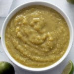 Salsa Verde in a white bowl with tomatillos and lime.