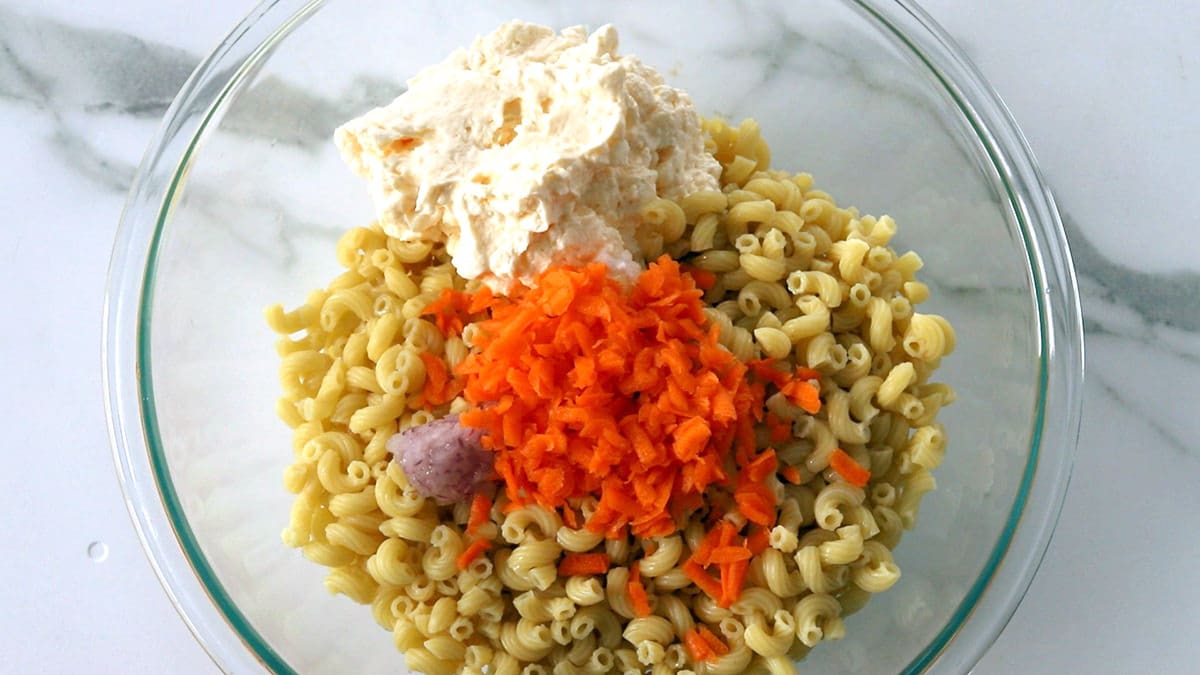 Clear bowl full of the ingredients to make Hawaiian Pasta Salad.