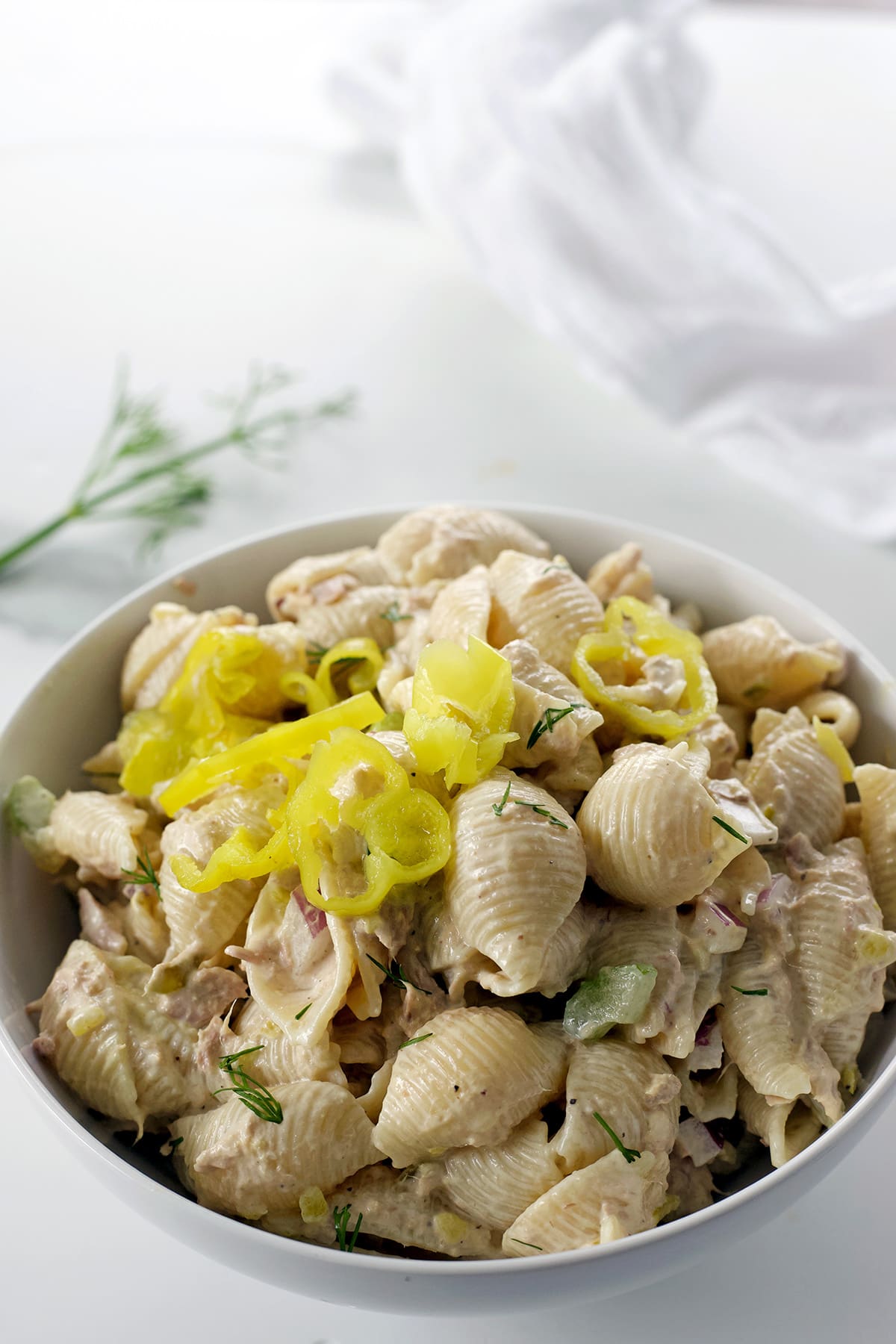 Pickled pepperoncini on top of a bowl of tuna pasta salad recipe.