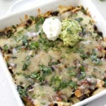 Baked Enchilada Casserole in a white baking dish topped with guacamole and sour cream.