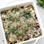 Baked Enchilada Casserole in a white baking dish topped with guacamole and sour cream.