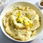 Mashed potatoes topped with butter in a white bowl.