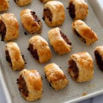 Puff pastry sausage rolls on a baking sheet.