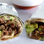 San Diego Style Carne Asada Burrito wrapped in foil and cut in half.