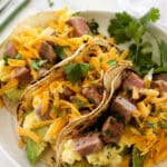 Three leftover prime rib breakfast tacos on a plate.